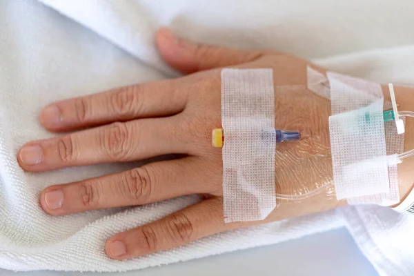 Woman's hand piercing needle to give saline solution