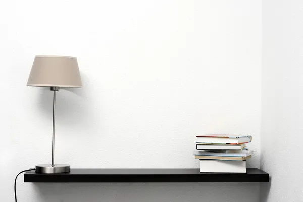 Bookshelf on the wall with lamp and books — Stock Photo, Image