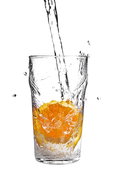 Pouring water into glass with orange slice on white — Stock Photo, Image