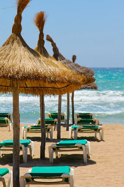 Tumbonas y sombrillas de paja en la playa — Foto de Stock