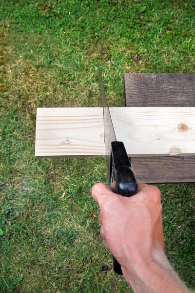 Plank op een groen gras achtergrond zagen — Stockfoto