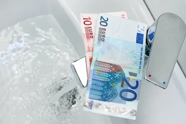 Dinheiro em euros na torneira e água corrente — Fotografia de Stock
