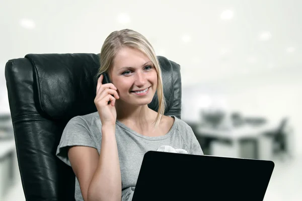 Young business woman using laptop and phone at office — Stock Photo, Image