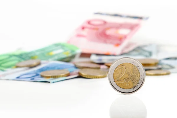 Muntstuk van twee euro met andere euro-muntstukken en bankbiljetten in achtergrond — Stockfoto