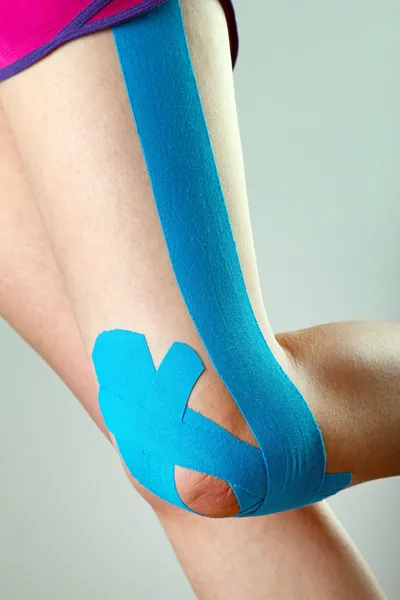 Therapeutic treatment of leg with blue physio tape — Stock Photo, Image