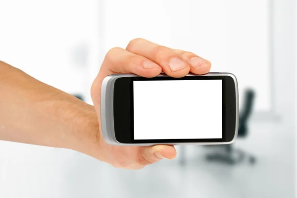 Mão segurando telefone inteligente móvel em branco no escritório — Fotografia de Stock