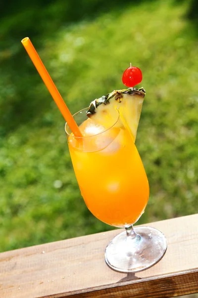 Glass of orange tropical cocktail on green grass background — Stock Photo, Image
