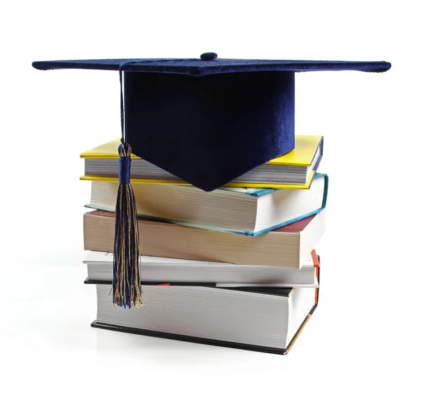 Sombrero de graduación y pila de libros aislados en blanco — Foto de Stock