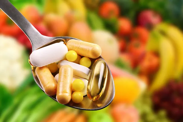 Spoon with dietary supplements on fruits background — Stock Photo, Image