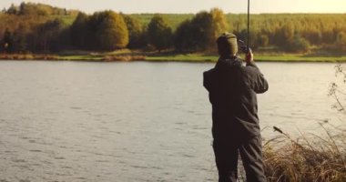 Balıkçı gün batımında gölde oltayla bir olta attı. deniz balıkçılığı