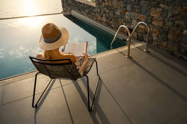 Relaxing Vacation Woman Sitting Chair Reading Book Terrace Swimming Pool — Stock Photo, Image