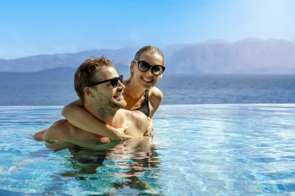 快乐的笑着的年轻夫妇在无穷无尽的游泳池里玩乐 浪漫的暑假 — 图库照片