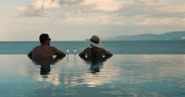 Paar entspannen zusammen im Infinity-Pool mit Meerblick und trinken Champagner im Luxus-Resort. Romantische Flitterwochen