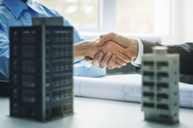 Gayrimenkul geliştirme - ticari ve apartman inşaatı projesinin başarılı anlaşmasının ardından işadamları tokalaşıyor