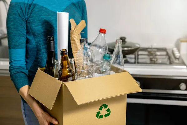 家庭の廃棄物の分別とリサイクル プラスチック ガラス 紙のゴミと段ボール箱を保持する女性 — ストック写真