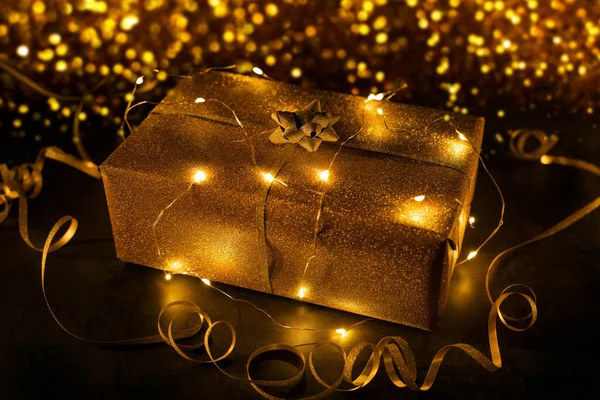 Regalo Oro Envuelto Luces Cuerda Sobre Fondo Bokeh Dorado —  Fotos de Stock