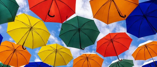 在蓝天的背景下挂着彩色的雨伞 — 图库照片