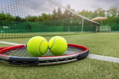 Tenis raketi ve toplar sentetik çim sahada.