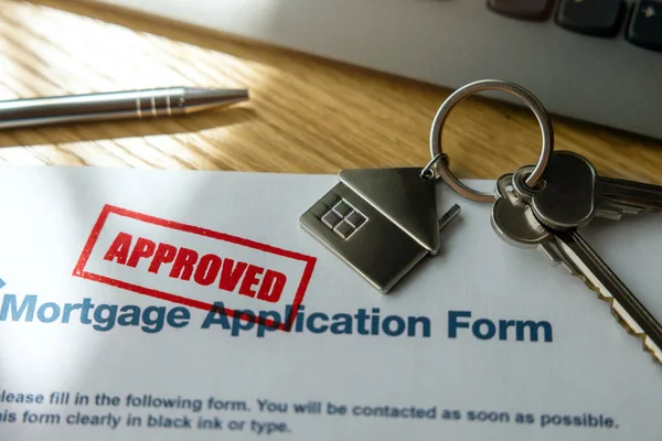approved mortgage loan application form and new house keys on the bank office table