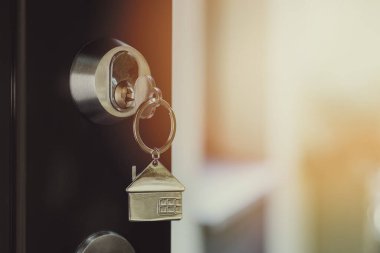 Kapının kilidinde anahtarlık olan bir anahtar. Yeni ev ve mülkiyet konsepti al. Boşluğu kopyala