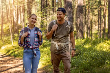 young couple with backpacks on a hike in forest. backpacking trip. summer adventure vacation