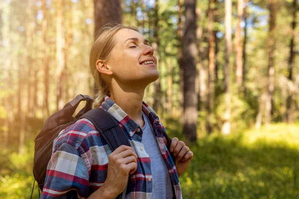woman backpacker enjoy the nature in forest with eyes closed. outdoor relaxing. stress relief, mental health