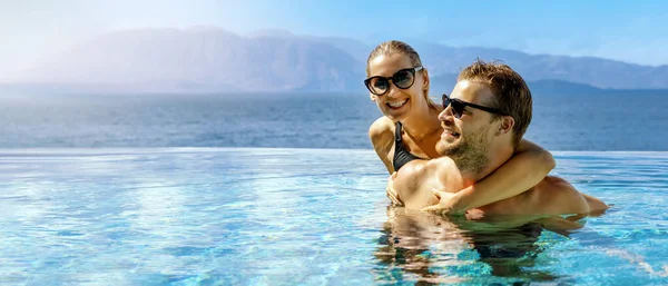 在成人度假胜地的无边无际的游泳池里 快乐的情侣们在一起 享受着海景的乐趣 浪漫的暑假 蜜月旅行 带有复制空间的横幅 — 图库照片