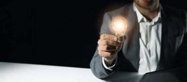 İş adamı elinde parlayan ampulü tutuyor. İş çözümleri, başlangıç ve yeni fikir kavramı. Kopyalama alanı olan pankart