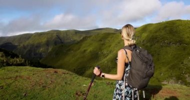 Kadın yürüyüşçü, dağların tepesindeki manzara manzarasının tadını çıkarıyor. Yürüyüş ve yürüyüş