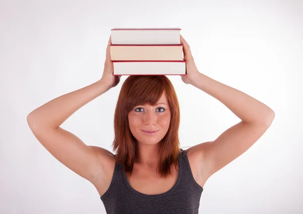 Молодая женщина носит книги на голове — стоковое фото