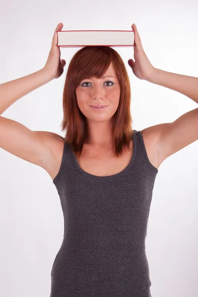 Een jonge vrouw is het dragen van boeken op haar hoofd — Stockfoto