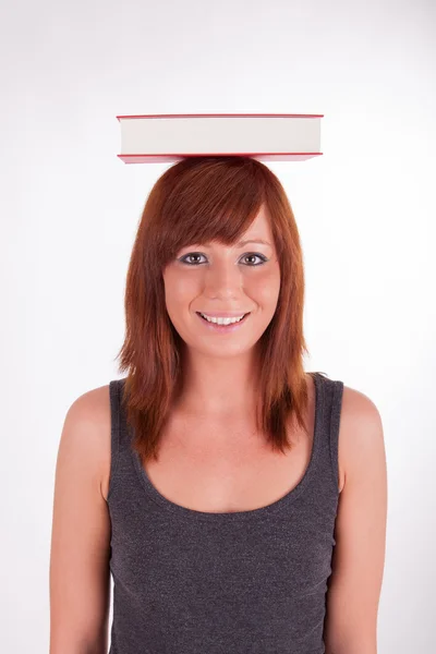 Een jonge vrouw is het dragen van boeken op haar hoofd — Stockfoto