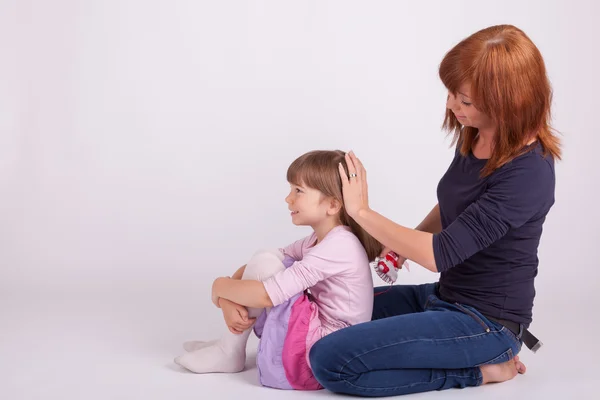 A mother is brushing her daughters hair — Stock Photo, Image