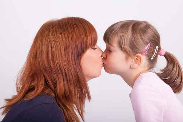 Een jonge moeder is haar dochter kussen — Stockfoto