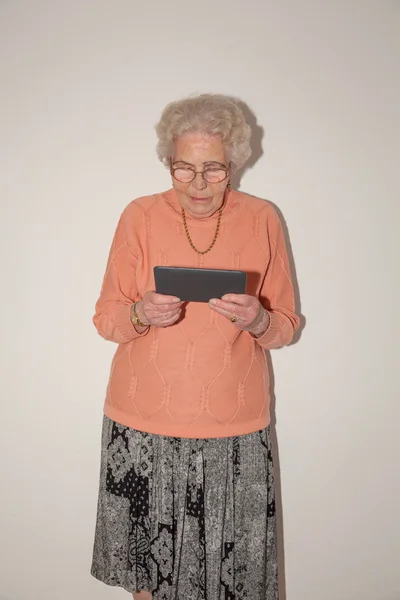 Uma mulher velha com um computador tablet — Fotografia de Stock