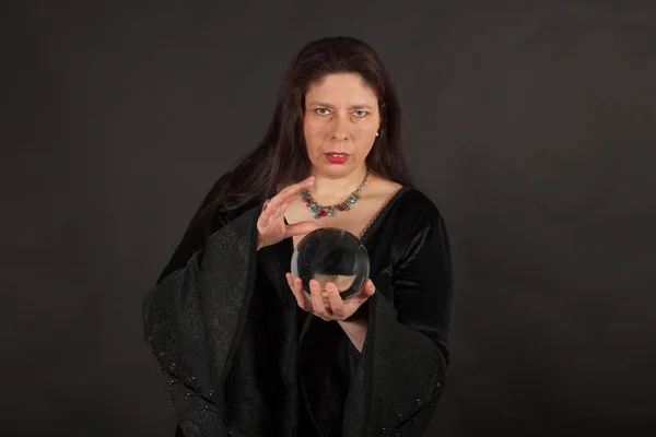 A woman is looking into a crystal ball — Stock Photo, Image