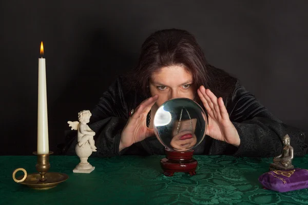 A woman is looking into a crystal ball — Stock Photo, Image