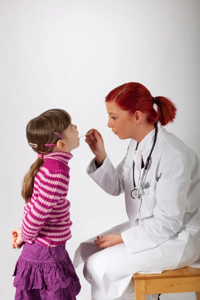 Ο παιδίατρος κοιτάζει ένα κοριτσάκι στο στόμα Royalty Free Φωτογραφίες Αρχείου
