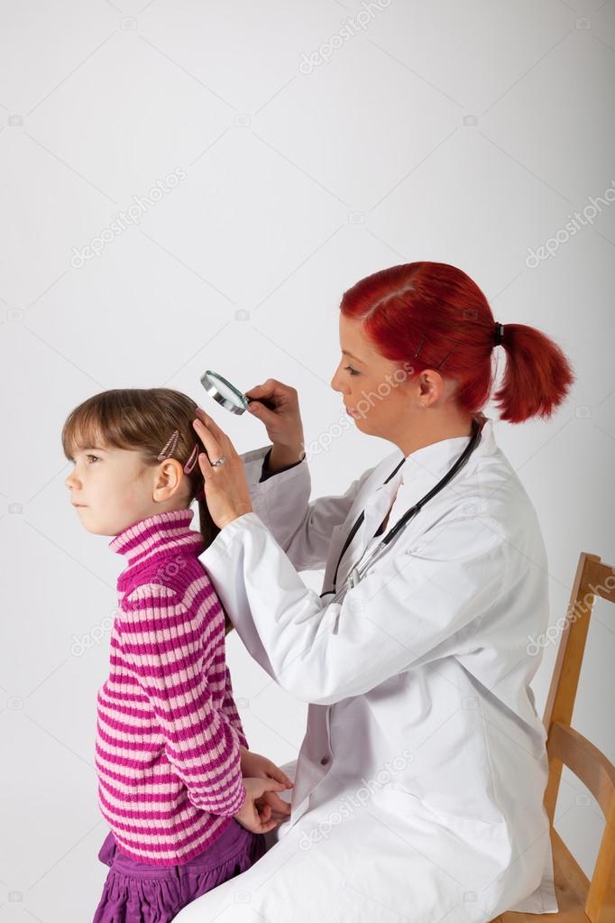 The pediatrician examines the head of a little girl