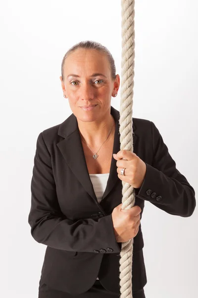 The young woman is climbing up a thick rope — Stock Photo, Image