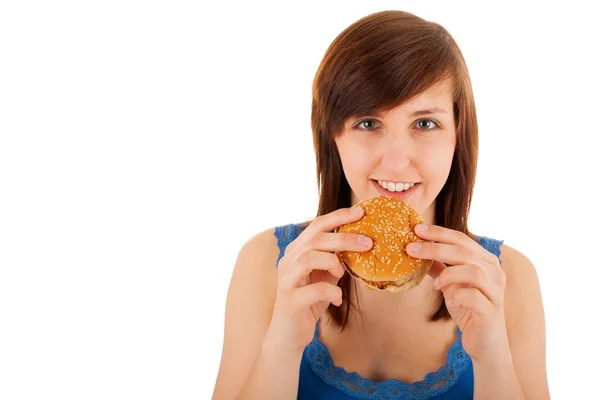 The young woman is eating a cheeseburger — Stock Photo, Image
