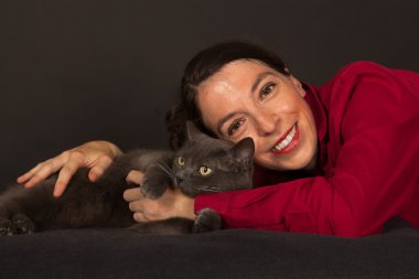 The young woman is cuddling with her cat