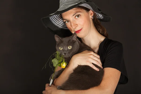 The young woman is holding the cat in her arms — Stockfoto