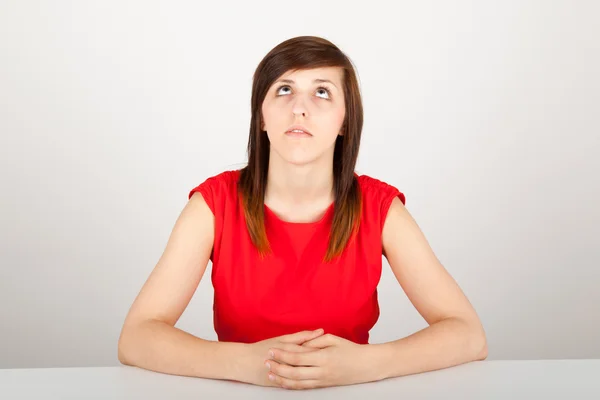 La joven está sentada aburrida en una mesa. — Foto de Stock