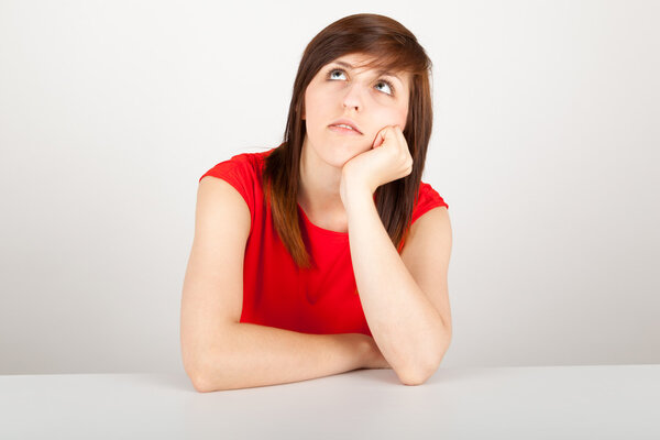 Молодая женщина сидит скучно за столом
