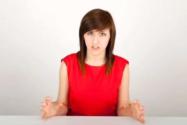 La joven está enojada sentada a la mesa. — Foto de Stock