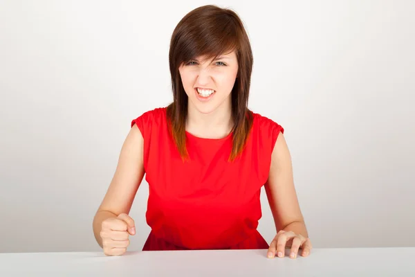 Молода жінка сердито сидить за столом — стокове фото