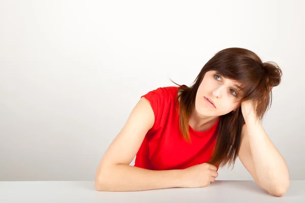 La joven está sentada aburrida en una mesa. —  Fotos de Stock