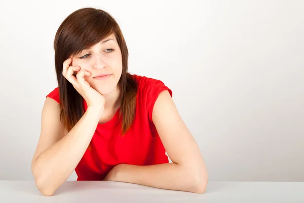 The young woman is sitting bored at a table — Stock Photo, Image