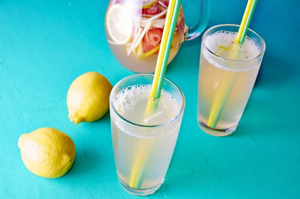 Koude zomer glaasje - limonade in werper met citroenen rond het — Stockfoto